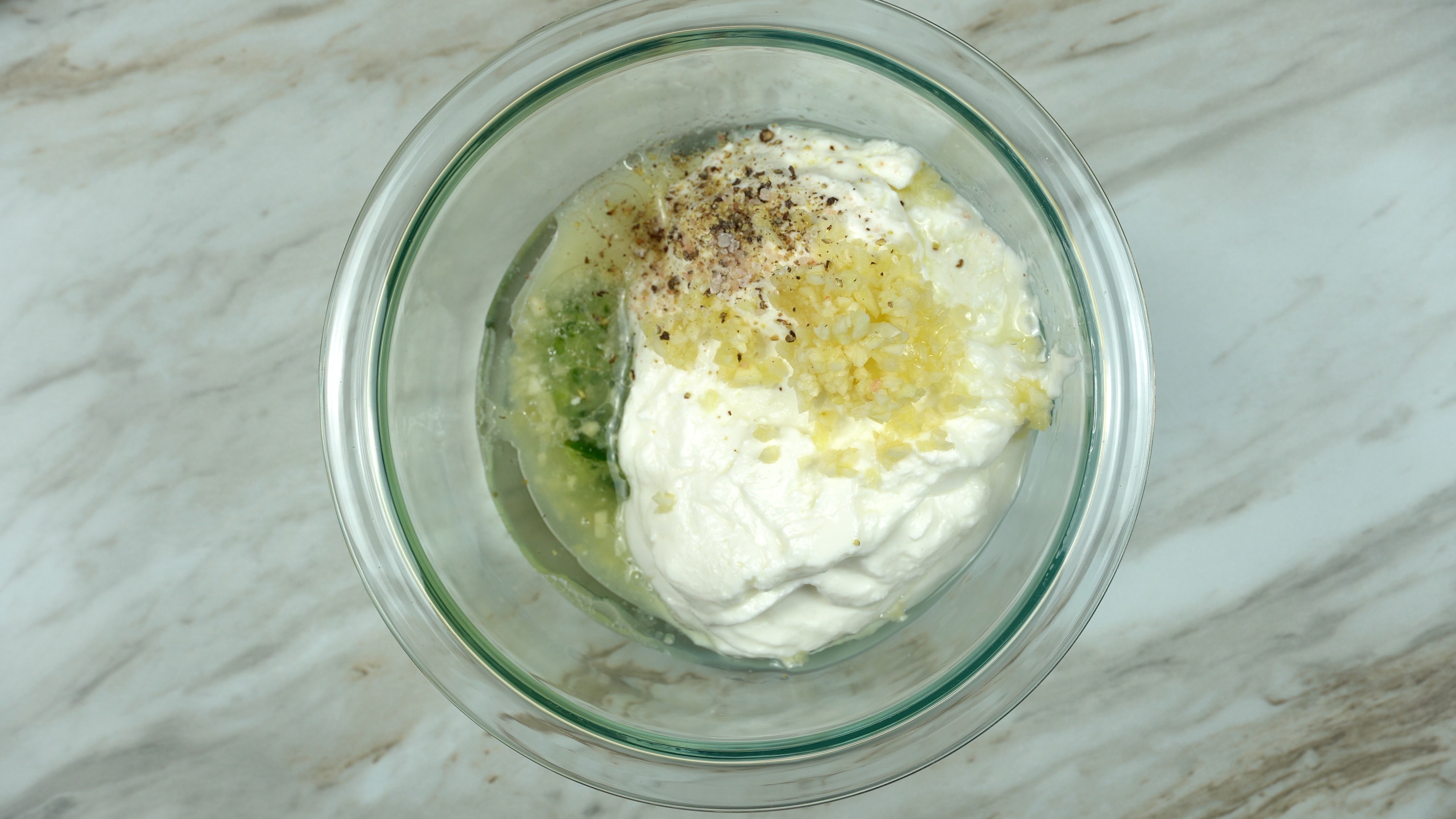 Tzatziki sauce in a glass bowl with cucumber slices